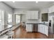 This kitchen features white cabinets, stainless appliances, and a dining area with stools at 440 S Alexander St, Buford, GA 30518