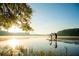 People paddleboard on a tranquil lake with views of trees and the rising sun at 4442 Mclain Cir, Acworth, GA 30101