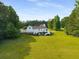 Expansive backyard showcasing a white home with a deck, surrounded by lush greenery and trees at 692 Brooks Woolsey Rd, Brooks, GA 30205