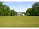 Picturesque white farmhouse set back on a large lot, surrounded by mature trees and a green lawn at 692 Brooks Woolsey Rd, Brooks, GA 30205