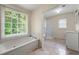 Bright bathroom featuring a soaking tub with a large window and a separate shower enclosure at 6553 Parkside Way, Tucker, GA 30084