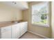 Functional laundry room with ample counter space, white cabinetry, and a bright window at 6553 Parkside Way, Tucker, GA 30084