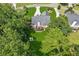 Aerial view of a home showcasing a large backyard, stone fire pit, wooden deck, mature trees, and a winding driveway at 6890 Autumn Hills Dr, Cumming, GA 30028