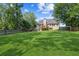 Lush backyard features green grass, mature trees, wooden deck, patio, and a stone fire pit, perfect for entertaining at 6890 Autumn Hills Dr, Cumming, GA 30028