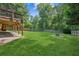 Expansive, grassy backyard with a wood fence, mature trees, and a stone fire pit for outdoor enjoyment at 6890 Autumn Hills Dr, Cumming, GA 30028