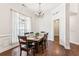 Bright dining room featuring a wooden table, chandelier, hardwood floors, and natural light from a large window at 6890 Autumn Hills Dr, Cumming, GA 30028
