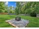 Outdoor stone fire pit with a metal grate, providing a cozy and inviting backyard gathering spot at 6890 Autumn Hills Dr, Cumming, GA 30028