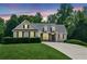 Charming home at dusk featuring a manicured lawn, mature trees, and a welcoming facade at 6890 Autumn Hills Dr, Cumming, GA 30028