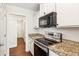 Bright kitchen features stainless steel appliances, granite countertops, white cabinetry, and hardwood floors at 6890 Autumn Hills Dr, Cumming, GA 30028