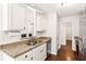 Kitchen with granite countertops, white cabinets, stainless steel appliances, and dark hardwood floors at 6890 Autumn Hills Dr, Cumming, GA 30028
