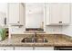 Updated kitchen featuring granite counters, white cabinets, and a view into the living room at 6890 Autumn Hills Dr, Cumming, GA 30028
