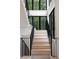 Staircase featuring white risers and black railings with large black framed windows offering wooded views at 130 Nova Ln, Roswell, GA 30075