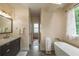 Modern bathroom featuring a soaking tub, natural light, neutral walls, and custom fixtures at 417 S Candler St, Decatur, GA 30030