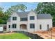 Newly built, a stunning two-story home features a light brick exterior, black-framed windows, and a charming arched entryway at 4608 Kings Down Rd, Atlanta, GA 30338