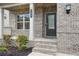 Close-up of the front door and porch featuring brick facade, elegant columns, and tasteful landscaping at 106 Logan Pass Dr, Loganville, GA 30052