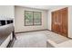 This carpeted bedroom features a wooden shuttered closet and large window at 6165 Pin Oak Ln, Alpharetta, GA 30005