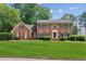 Beautiful two-story brick home with a manicured green lawn and mature trees at 6165 Pin Oak Ln, Alpharetta, GA 30005