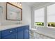 Bright bathroom featuring a blue vanity with marble countertop and a window overlooking the landscape at 115 Trinity Hollow Dr, Canton, GA 30115