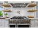 Close up of the kitchen range, with pot filler, floating shelves, white subway tile and marble countertops at 115 Trinity Hollow Dr, Canton, GA 30115