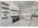 Bright kitchen with stainless steel appliances, white cabinets, floating shelves, and marble countertops at 115 Trinity Hollow Dr, Canton, GA 30115
