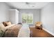 Bright bedroom with a queen-size bed, a woven chair, and a window overlooking the lush green outdoors at 5258 Tallgrass Nw Way, Kennesaw, GA 30152