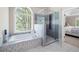 Bright bathroom with a soaking tub under a window and a glass shower stall at 5258 Tallgrass Nw Way, Kennesaw, GA 30152