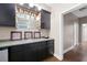 Stylish wet bar with dark cabinets, glass shelving, and a mini-fridge, perfect for entertaining guests at 5258 Tallgrass Nw Way, Kennesaw, GA 30152
