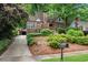 Charming brick home with manicured front yard, mature landscaping, and a long driveway leading to a garage at 1291 Stillwood Ne Dr, Atlanta, GA 30306