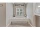 Inviting bathtub with a decorative window and a tiled platform at 2073 Woodside Park Dr, Woodstock, GA 30188