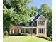 Charming two-story brick home with a lush front yard, mature trees, and a welcoming facade at 2073 Woodside Park Dr, Woodstock, GA 30188