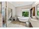 Bright bathroom featuring a freestanding tub, walk-in shower, and double sink vanity with elegant countertop and chandelier at 635 Piping Rock Pt, Lawrenceville, GA 30043