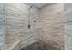 Detailed shot of the tile shower showcasing a stone floor, built in seat, and modern fixtures at 635 Piping Rock Pt, Lawrenceville, GA 30043