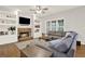 Cozy living room with a stone fireplace, built-in shelves, a ceiling fan, and a comfortable sectional sofa at 224 Mountain View Dr, Woodstock, GA 30188