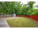 Expansive backyard with lush greenery, an outbuilding, a patio, and a red fence at 3479 Thompson Dr, Atlanta, GA 30331