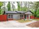 A cozy single-story home with gray siding, a red privacy fence, a covered porch and a driveway at 3479 Thompson Dr, Atlanta, GA 30331