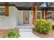 Inviting entryway with an orange door, white brick, and manicured greenery at 3614 N Druid Hills N Rd, Decatur, GA 30033