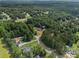 Aerial view of a home nestled among green trees with a long driveway and sprawling yard in a neighborhood at 385 Eagles Nest Cir, Carrollton, GA 30116