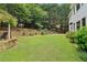 Large grassy backyard featuring mature trees, stone retaining walls, and outdoor recreation area at 4085 Hillcrest View Ct, Suwanee, GA 30024