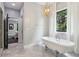 Bright bathroom with a freestanding tub, decorative light fixture, and a large window at 4085 Hillcrest View Ct, Suwanee, GA 30024