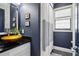 Stylish half bath with dark blue walls, a vessel sink, and unique shower curtain with natural light at 4085 Hillcrest View Ct, Suwanee, GA 30024