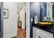 Elegant half bath featuring blue accent wall, vessel sink, black granite countertop, and access to hallway at 4085 Hillcrest View Ct, Suwanee, GA 30024