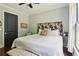 Comfortable bedroom with decorative headboard, hardwood floors, neutral paint color, and side windows at 4085 Hillcrest View Ct, Suwanee, GA 30024