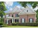 Charming brick home with a well-maintained lawn, gray shingle accents, and black shutters under a partly cloudy sky at 4085 Hillcrest View Ct, Suwanee, GA 30024