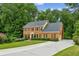 Elegant brick home with a lush green lawn, long driveway, and surrounded by mature trees at 5524 Wedgewood Sw Ct, Lilburn, GA 30047