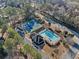 Aerial view of a community pool and tennis court surrounded by lush greenery and well-maintained landscaping at 735 Amberton Close, Suwanee, GA 30024