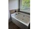 A soaking tub with tiled backsplash set under a window at 4482 Ridge Mill Ne Ter, Douglasville, GA 30135