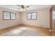 A bedroom featuring hardwood floors, two windows for ample light, and a ceiling fan for comfort at 5670 Lanny Dr, Powder Springs, GA 30127
