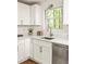 Bright kitchen with shaker cabinets, modern hardware, stone countertops, stainless dishwasher, and window to backyard at 5999 Brookside Se Ln, Mableton, GA 30126