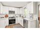Bright kitchen features white cabinetry, stainless steel appliances, stone countertops and a window for natural light at 5999 Brookside Se Ln, Mableton, GA 30126