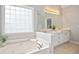 Bright bathroom with jacuzzi tub, double sink, granite countertops and cabinet storage at 180 Mirramont Lake Dr, Woodstock, GA 30189